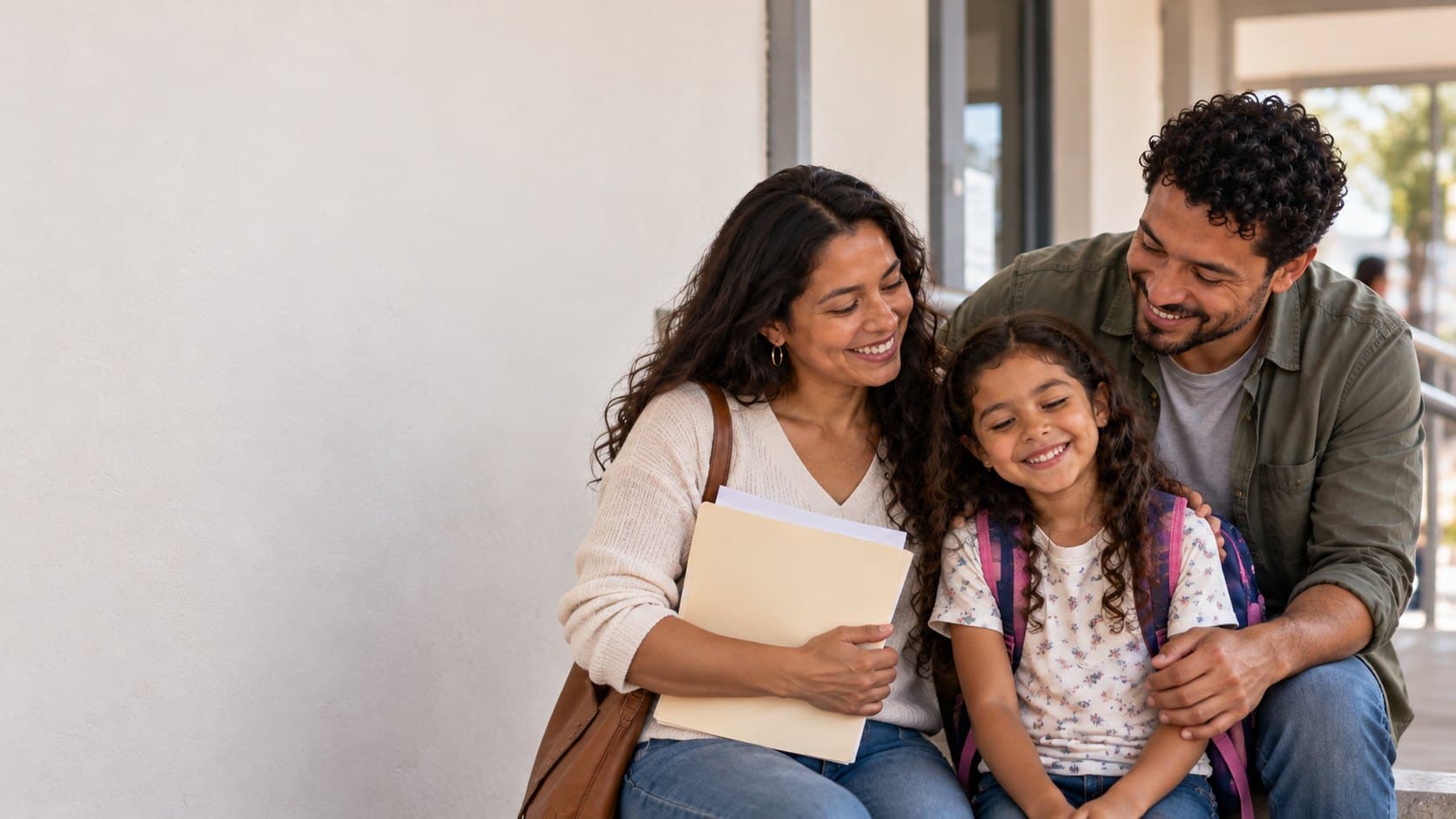 Familia latinoamericana sonriendo junto a la entrada de un edificio de servicios